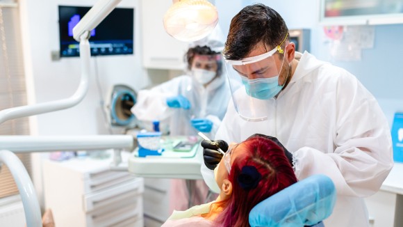 BDJ Jobs Collection Hero Image Photograph from a dental practice surgery, with the dentist leaning over his patient and an assistant in the background