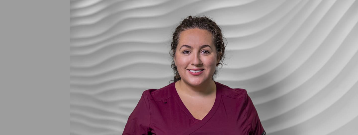 SECONDARY Hero 1440X545px MEMBERSHIP AW A female dentist wearing burgundy scrubs looking confidently into the camera
