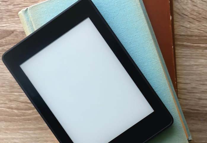 A Kindle On Top Of A Stack Of Books A blank kindle on top of a stack of books