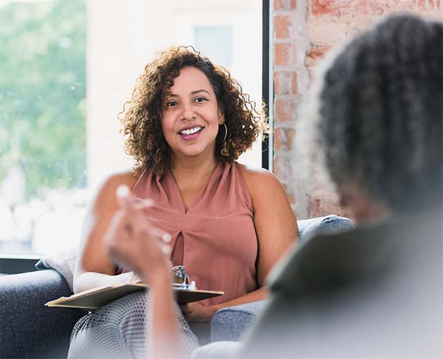 Chase de Vere 3 Two women seated in a bright room engaged in conversation