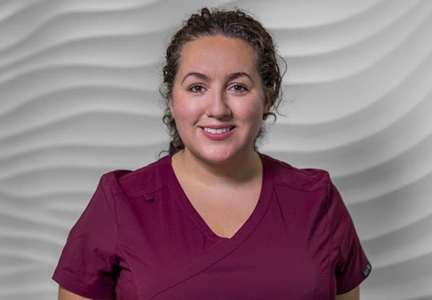 Membership AD A female dentist wearing burgundy scrubs looking confidently into the camera